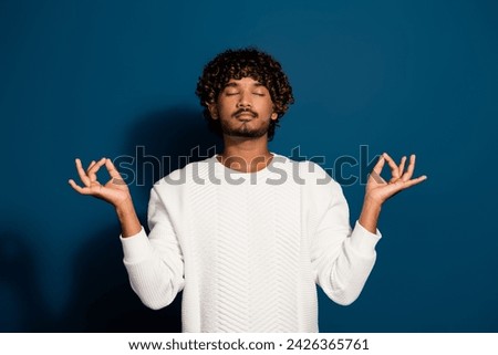 Portrait of young guy in asana position balance chakra closed eyes meditation retreat relax isolated on dark blue color background