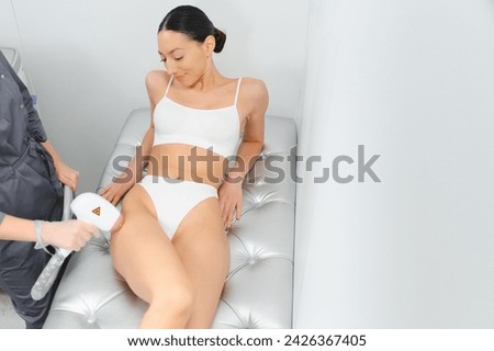 Laser epilation and cosmetology in beauty salon. Beautiful brunette woman getting hair removing on legs.