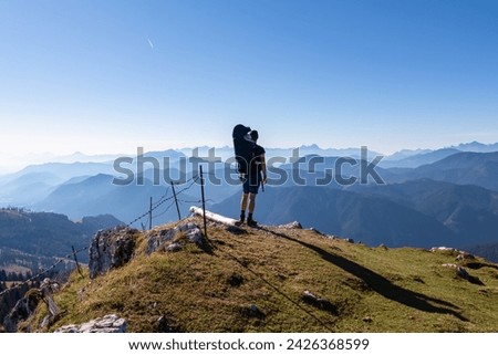 Man with baby carrier looking at magical mountain peaks of Karawanks and Julian Alps seen from Goldeck, Latschur group, Gailtal Alps, Carintha, Austria. Mystical atmosphere in Austrian Alps in summer Royalty-Free Stock Photo #2426368599