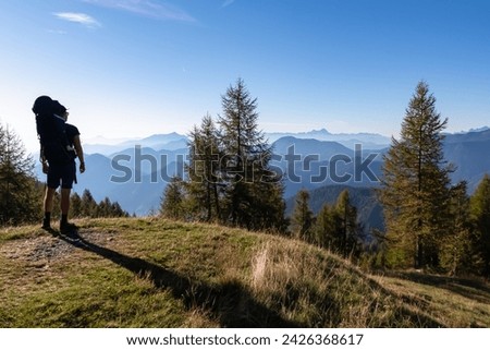Man with baby carrier looking at magical mountain peaks of Karawanks and Julian Alps seen from Goldeck, Latschur group, Gailtal Alps, Carintha, Austria. Mystical atmosphere in Austrian Alps in summer Royalty-Free Stock Photo #2426368617