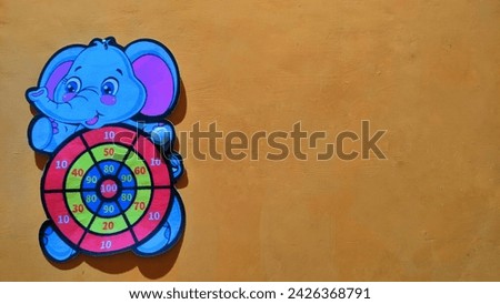 The target dart is in the shape of an elephant cartoon character on an orange background, shoot on target