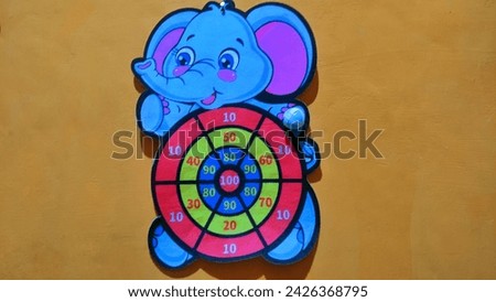 The target dart is in the shape of an elephant cartoon character on an orange background, shoot on target