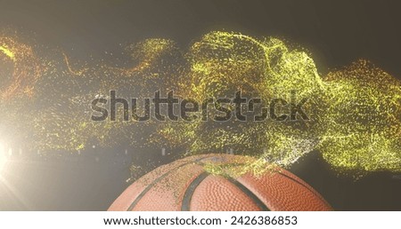 Image of glowing gold particles moving over basketball. sport and competition concept, digitally generated image.