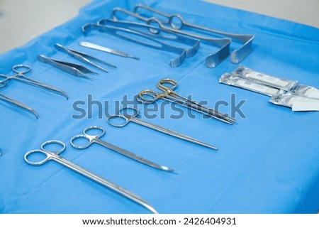 surgical instruments and tools including scalpels, forceps and tweezers arranged on a table for a surgery, Sterilized surgical instruments on the blue wrap	 Royalty-Free Stock Photo #2426404931