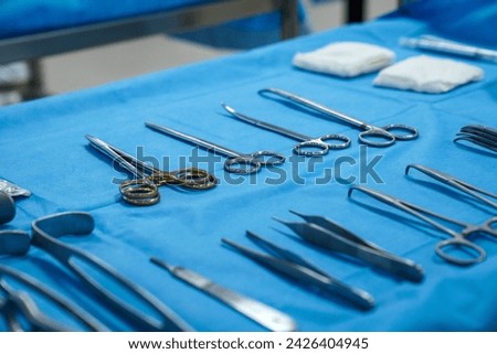 Sterile surgical instruments and tools including scalpels, scissors, forceps and tweezers arranged on a table for a surgery, Sterilized surgical instruments on the blue wrap	 Royalty-Free Stock Photo #2426404945