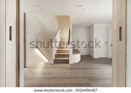 Entrance hall of a detached house with a wooden seat with large drawers underneath next to stairs with wooden steps and handrails with LED light strips Royalty-Free Stock Photo #2426406487