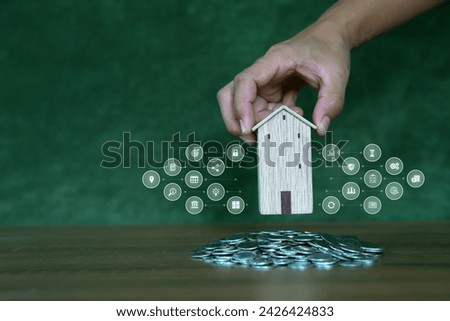 Hand choose house with coins pile with business symbols icons for real estate or money savings plan ideas and investment planning goal to growth and bank home loan or financial insurance.
