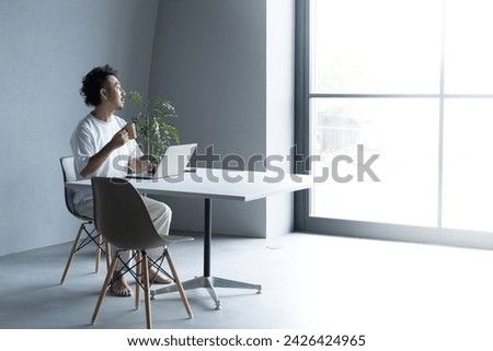 Minimalist man working in a white room with a computer open, image of an engineer, freelancer, etc. wide angle