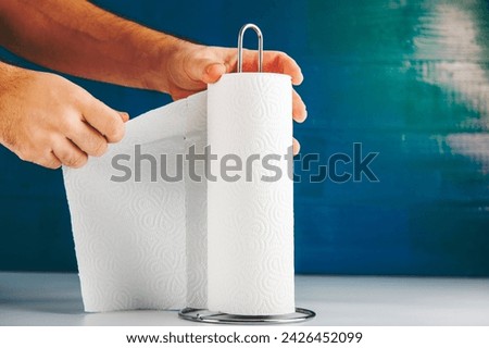 an anonymous hand is tearing off paper towel, hygiene concept copy space includes.