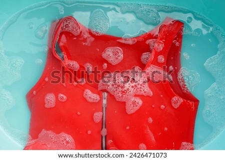 Women's dress soaked in water dissolved detergent with white foam bubble. Laundry concept