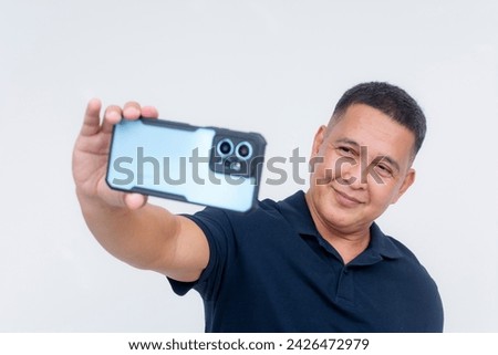 A middle aged asian man takes a selfie with his high-end cellphone. Advertisement of phone camera features and lens. Isolated on a white background.