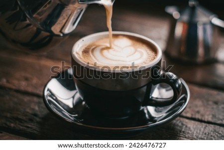 A picture of a hot and delicious cup of coffee with smoke, which expresses the splendor of coffee, on a plate that reflects the lights, and a brown colored place with white lighting.