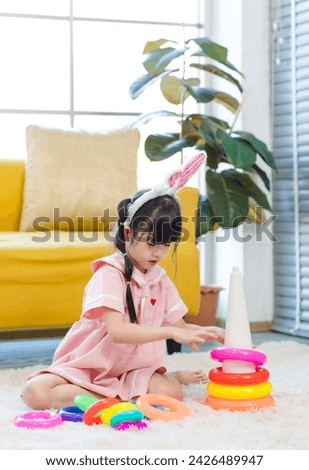 Happy asian child little girl cute wearing bunny ears headbands playing colorful toy plastic on floor in living room at home have fun. Concept of parenting child development.