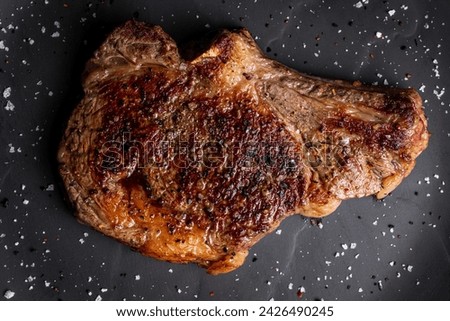 flat lay picture of bone in rib eye steak on black stone board