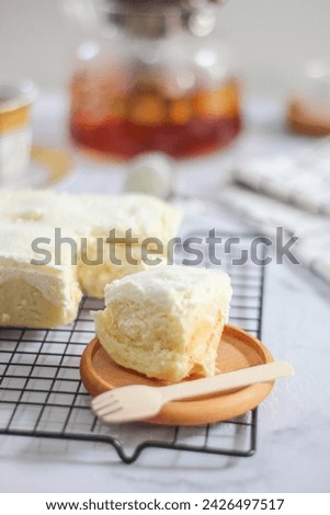 Milk Bun Thailand is a soft bread with a topping of powdered sugar, milk and vla filling, soft focus texture, served on black tray and cup of tea with a piece of milk bun. makanan viral indonesia Royalty-Free Stock Photo #2426497517