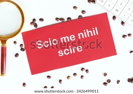 Scio me nihil scire It is translated from Latin as I know I don't know anything. It's written on the red card