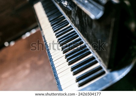 A black and white piano, a musical instrument, is placed in a dimly lit room, surrounded by darkness