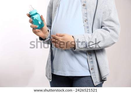 Pregnant woman with baby bottle on white background, closeup