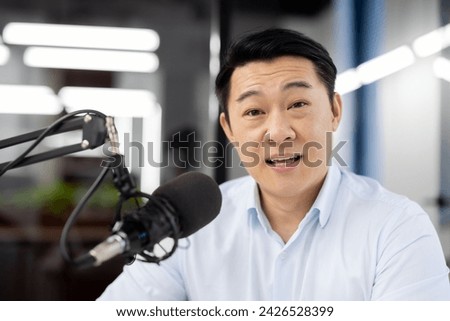 Asian male broadcaster speaking into microphone in a professional recording studio, showcasing communication.