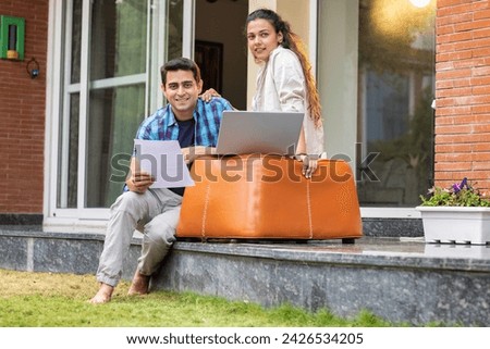 Smiling young couple using laptop while sitting together at home