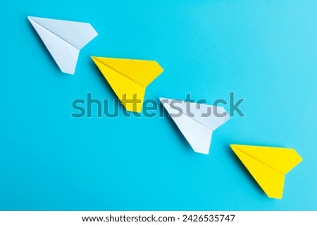 Top view of white and yellow paper airplanes origami flying on blue background