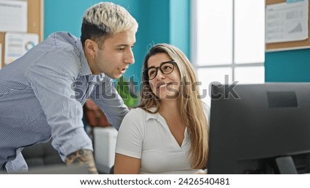 Two workers man and woman working together speaking at the office