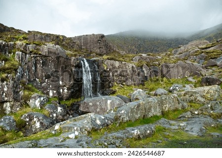 Small waterfall at the Conor Pass, one of the highest Irish mountain passes served by an asphalted road, located on the south-western end of the Dingle Peninsula, County Kerry, Ireland Royalty-Free Stock Photo #2426544687