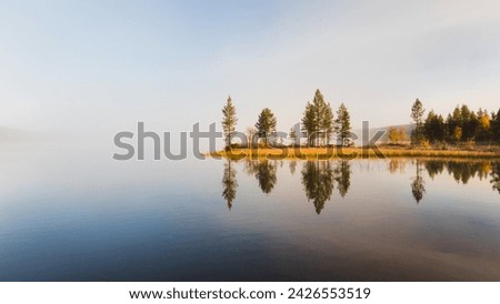 Calm water reflects trees during autumn morning in the lapland nature, Finland Royalty-Free Stock Photo #2426553519