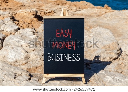 Easy money business symbol. Concept words Easy money business on beautiful black chalk blackboard. Beautiful red stone blue sea background. Easy money business concept. Copy space.