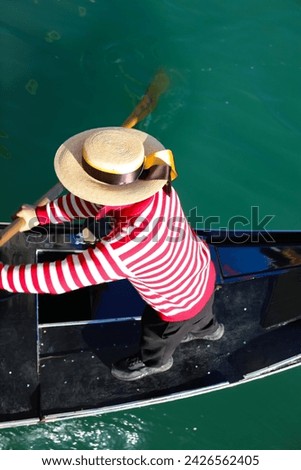 Venetian gondolier with hat rowing on gondola boat on the water of grand canal in Venice in Italy Royalty-Free Stock Photo #2426562405