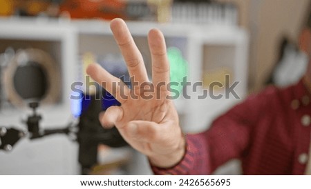 In the heartbeat of the mic, young hispanic man nails live radio show with a thrilling countdown, his three fingers showing time ticking in the upbeat radio studio