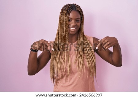 African american woman with braided hair standing over pink background looking confident with smile on face, pointing oneself with fingers proud and happy.  Royalty-Free Stock Photo #2426566997