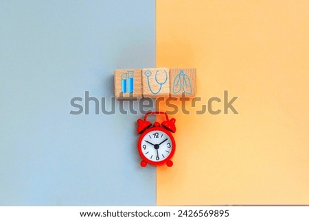 alarm clock.wood cubes with  healthcare medical icons on the background. health treatment and prevention, health care concept.