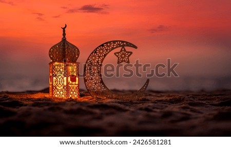 Traditional lantern lamp with crescent moon on the beach during sunset, Ramadan Kareem and Eid Mubarak greeting banner image Royalty-Free Stock Photo #2426581281