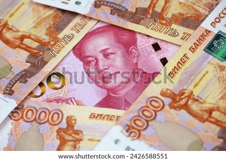 Chinese yuan banknote surrounded by russian rubles. Concept of economic cooperation between the China and Russia, trading and support Royalty-Free Stock Photo #2426588551