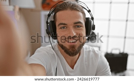 Young hispanic man listening to music make selfie picture by camera at music studio