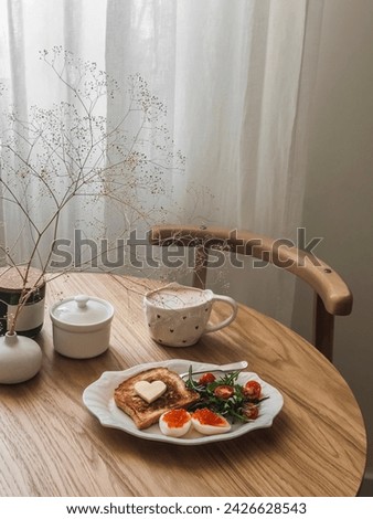 Romantic Valentine's Day breakfast, brunch - coffee, toast, eggs with red caviar and salad on a round wooden table