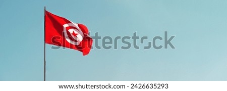 Banner flag of Tunisian Republic on background of blue sky