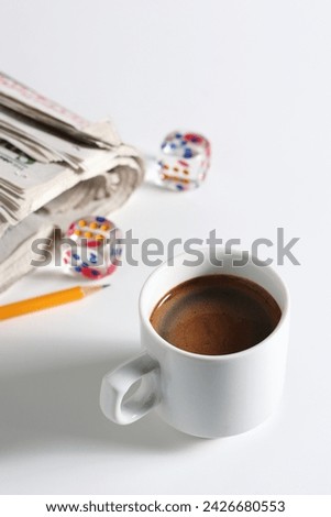 Cup of coffee, newspaper and transparent dice on a white background Royalty-Free Stock Photo #2426680553