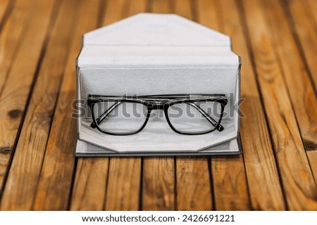 Stylish, fashionable glasses with clear lenses for good vision with black frames lie in a leather case on a wooden background. Photography, business concept, work accessories.