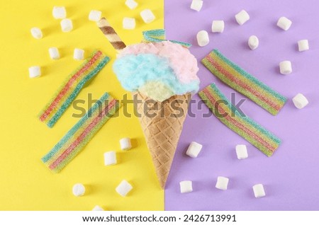 Sweet cotton candy in waffle cone and marshmallows on color background, flat lay