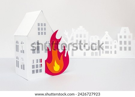 House and flame of color paper cut on gray background. Fire safety concept. Selective focus, copy space