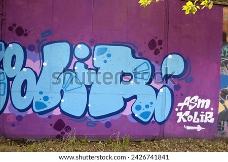 The old wall decorated with paint stains in the style of street art culture. Colorful background of full graffiti painting artwork with bright aerosol outlines on wall. Colored background texture