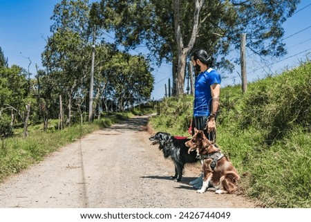 Man jogging with his dogs on a sunny day. Colombian nature. Man exercising with his pets. Man training his dogs. Happy dogs.