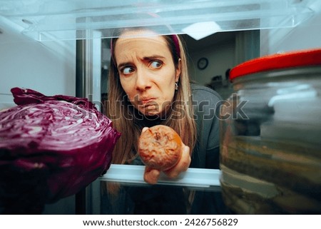 
Woman Taking out a Rotten Fruit from her Fridge. Disgusted girl having her stomach turning from bad spoiled foods 
 Royalty-Free Stock Photo #2426756829