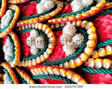 In the picture, orange corn seeds, green string, and white amaranth flowers are decorated into a very beautiful pattern.