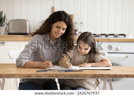 Female nanny spend time with little cute girl painting pictures together in paper album. Loving mom teach her adorable preschooler daughter to draw paintings, enjoy creative hobby and leisure at home
