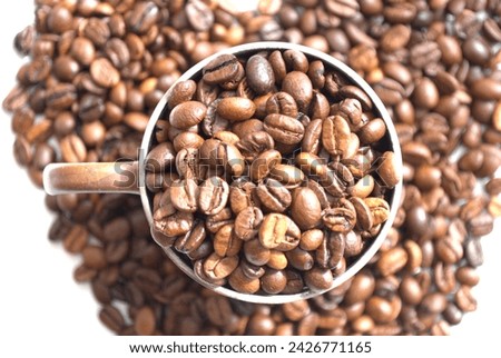 Coffee beans in a cup and coffee beans spread out on the table. An image of a relaxing coffee time.
