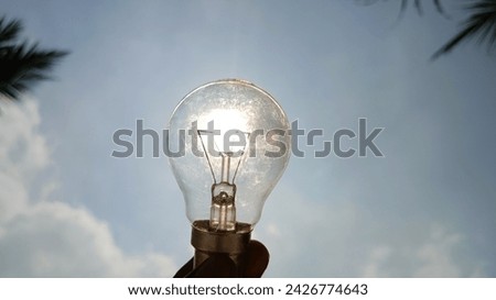 Bulb silhouette against vibrant sky, symbolizing innovation and energy. Conceptual image of bulb as sun.