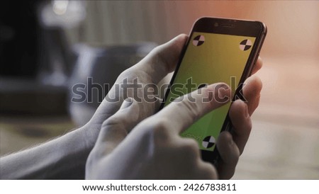 Close up of hands using smartphone with green screen, sliding and tapping on blurred kitchen table background. Man hands holding mobile phone with chroma key.